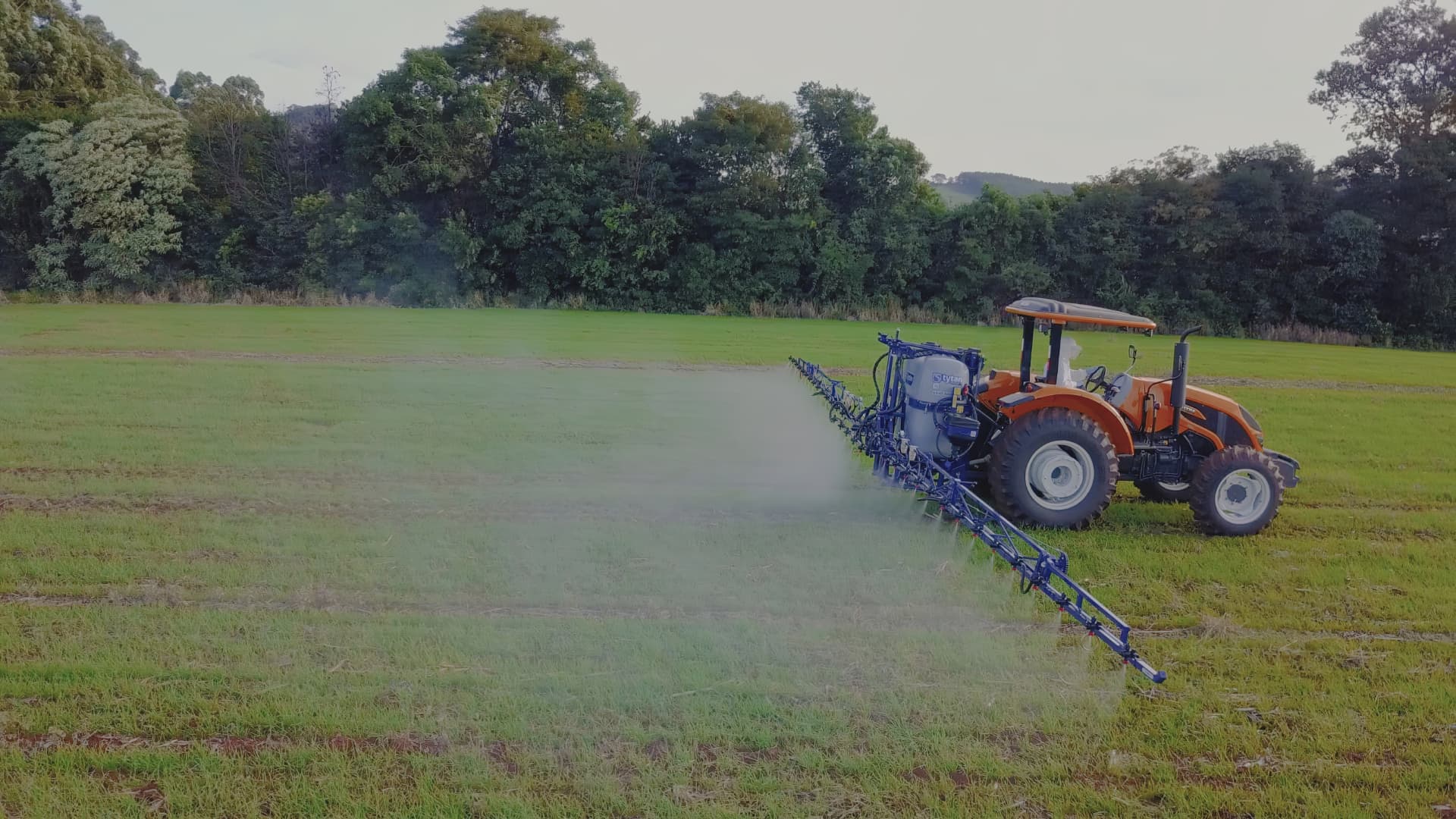 Trator com pulverizador em operação no campo